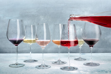 Rose wine poured into a glass at a tasting, with white and red wine of various colors. Winetasting...