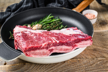 Fresh Raw beef short ribs meat on a pan with herbs. wooden background. Top view