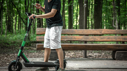 Young man in a city park with an electric scooter.