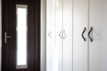 Close-up of black knobs on a white cabinet.