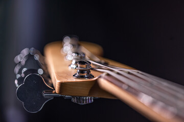 Close-up of a bass guitar fretboard on a blurred dark background. - obrazy, fototapety, plakaty