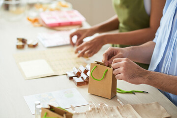 Business couple packing handmade soap bars and essential oil in bags to sell online and deliver to customers