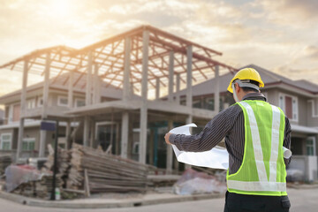 Fototapeta premium young professional engineer in protective helmet and blueprints paper at the house building construction site