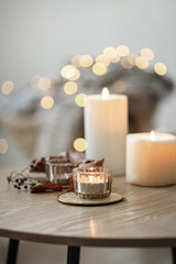 Cozy home composition with candles on blurred bokeh background.