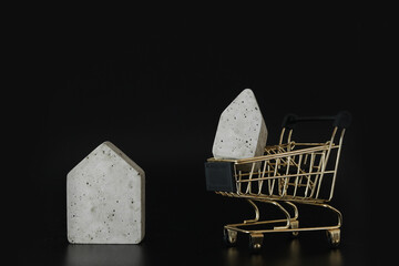 Buy or rent, choice. House model in mini shopping cart on the black background. Buy a house....