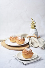 luxury home made chilled vanilla cream puff pastry choux with sugar powder on wood plate and cloth in white marble background dessert halal menu