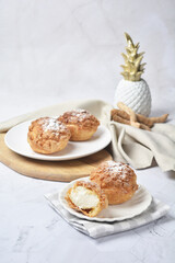 luxury home made chilled vanilla cream puff pastry choux with sugar powder on wood plate and cloth in white marble background dessert halal menu