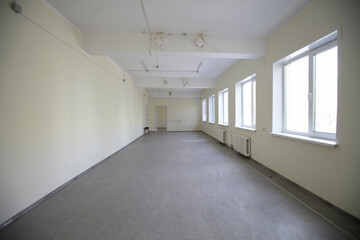 Empty white corridor with windows and gray floor.