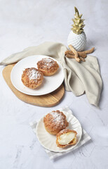 luxury home made chilled vanilla cream puff pastry choux with sugar powder on wood plate and cloth in white marble background dessert halal menu