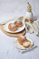 luxury home made chilled vanilla cream puff pastry choux with sugar powder on wood plate and cloth in white marble background dessert halal menu