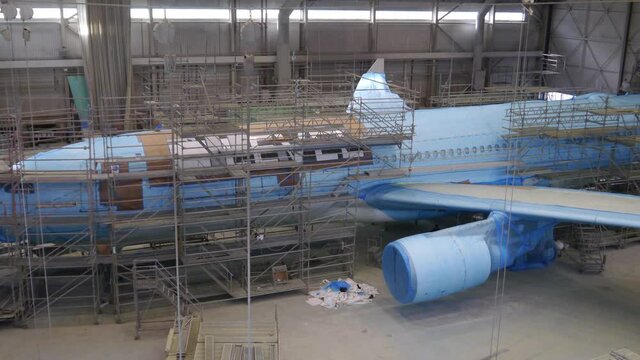 Workers painting airplane in hangar