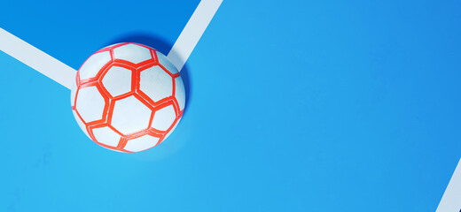White futsal soccer ball with orange hexagon in the corner of an indoor soccer field with copy space