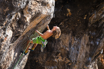 A young athlete climbs a rock