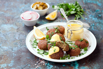 Homemade vegan lentils and vegetables baked burgers cutlets or patties, coconut yogurt sauce with turmeric and spices on a white plate, selective focus