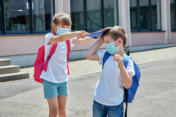A girl and a boy in the school yard. A girl hits a schoolboy on the head with a notebook. Bullying...