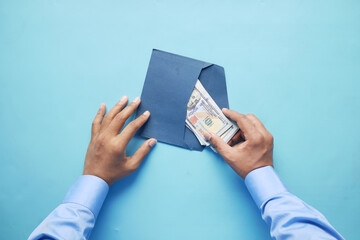 person hand putting cash in a envelope, top view 