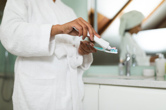 Mixed race woman in bathroom holding toothpaste and toothbrush