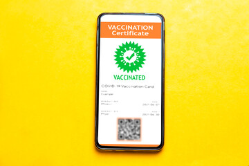 digital vaccination certificate in mobile phone on yellow background. this app is to certify that have been vaccinated of coronavirus covid-19