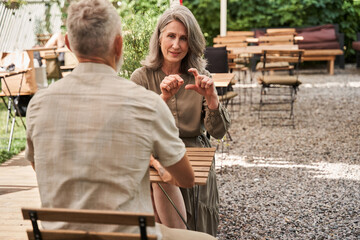 Woman telling something to her lovely man while sitting at the summer cafe