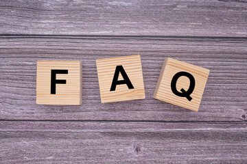 The FAQ word is written on wooden cubes on wooden table background. Frequently asked questions. Top...