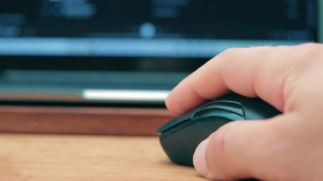 Hand uses the wireless mouse for working with laptop or computer on the desk table, extreme close up view