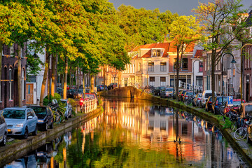 Delt canal with old houses and cars parked along on sunset