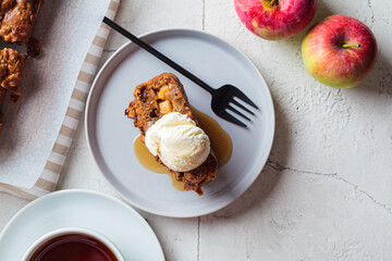 Apple bread with a scoop of ice cream and maple syrup on a gray plate. Autumn fruit pie, gray background.