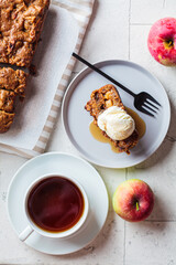 Apple bread with a scoop of ice cream and maple syrup on a gray plate. Autumn fruit pie, gray background.