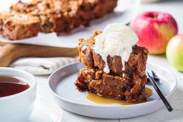 Apple bread with a scoop of ice cream and maple syrup on a gray plate. Autumn fruit pie, gray...