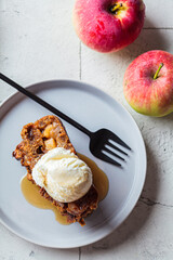 Apple bread with a scoop of ice cream and maple syrup on a gray plate. Autumn fruit pie, gray...
