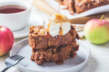 Apple bread with a scoop of ice cream and maple syrup on a gray plate. Autumn fruit pie, gray background.