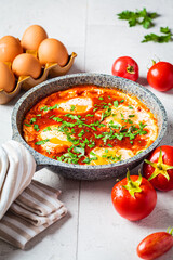 Traditional Israeli shakshuka in gray frying pan. Fried eggs in tomato sauce.