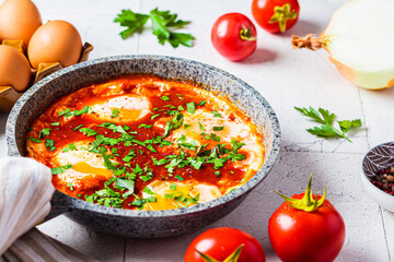 Traditional Israeli shakshuka in gray frying pan. Fried eggs in tomato sauce.