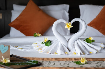 Fototapeta na wymiar White two towel swans and some flowers on the bed in Honey moon suit