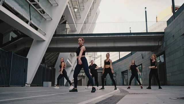 Close up portrait of diverse group of six stylish professional dancers performing a zumba dance routine in front of city view