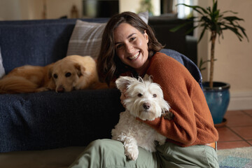 Portrait of smiling caucasian woman in living room sitting on floor embracing her pet dog