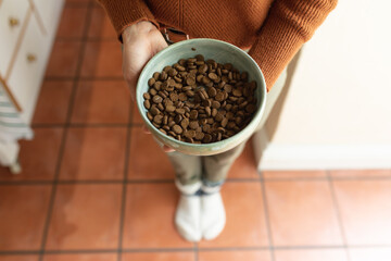 Close up of caucasian woman in kitchen, holding bowl of dog food
