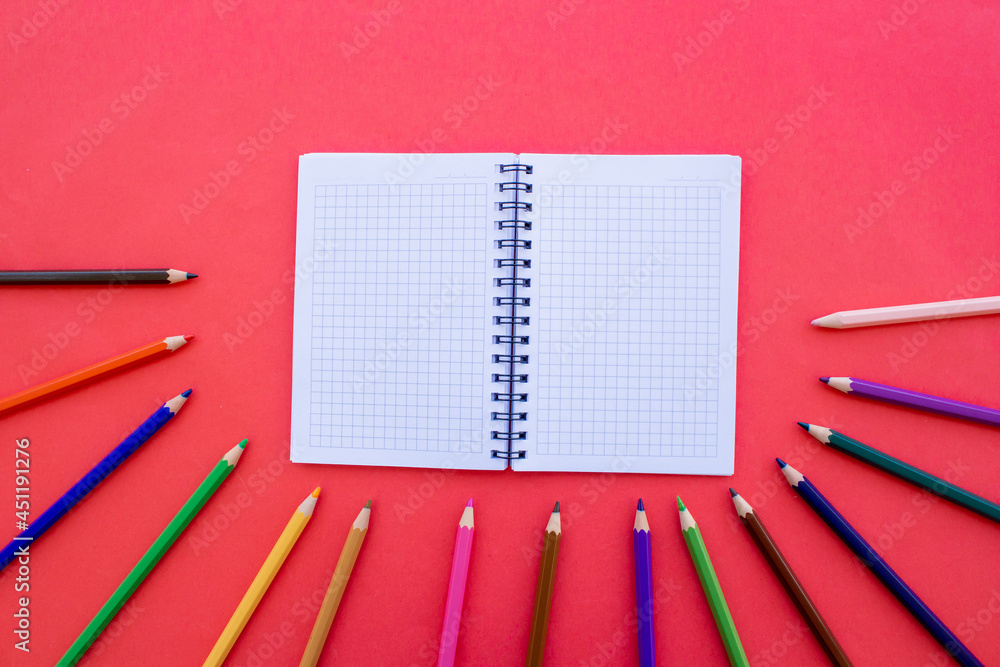 Poster colorful crayons and empty notepad isolated on red background. back to the school concept.