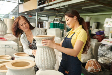 Plant market worker helping customer to find the best pot for her houseplant