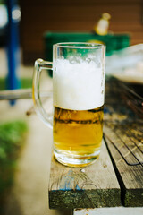 glass of beer with foam on the table in the garden. octoberfest 