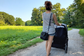Giovane donna che passeggia con i suoi gemelli nel parco in estate
