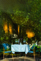 Spectacular interior of of Living room, stylish decor.Table, chairs, cutlery and wine glasses. Glass wall
