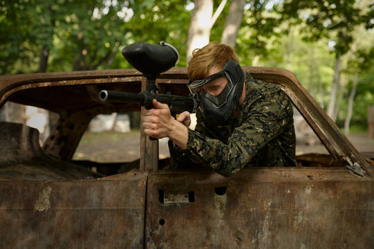 Paintball player in uniform and mask in forest