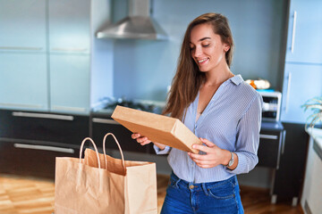 Smiling satisfied happy casual adult joyful young millennial girl customer received cardboard bags...