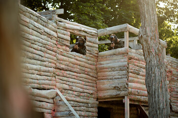 Two paintball warriors shoots from the shelter