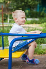 Fototapeta na wymiar Blonde little boy in a summer park