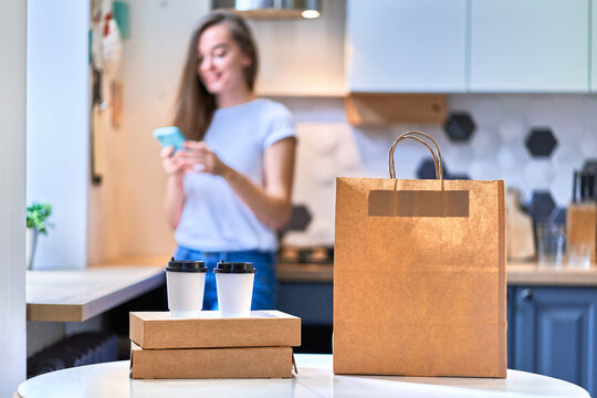 Modern busy cute smiling joyful happy casual millennial woman received cardboard bags and paper cups with takeaway food and drinks. Fast home delivery concept