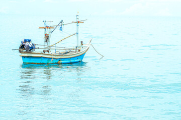 Fototapeta na wymiar Small fishing boat floating in blue sea with blue sky 