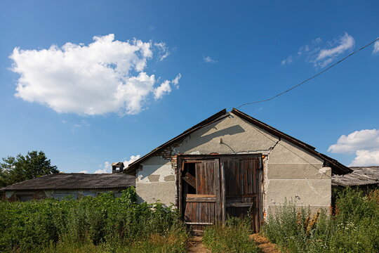 building of an old abandoned farm on a background of blue sky, summer.