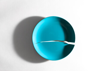 Crack in blue plate on white background, rift between two parts of dishware, blue plate broken into two pieces, white background, crack, split, rupture, fracture, china